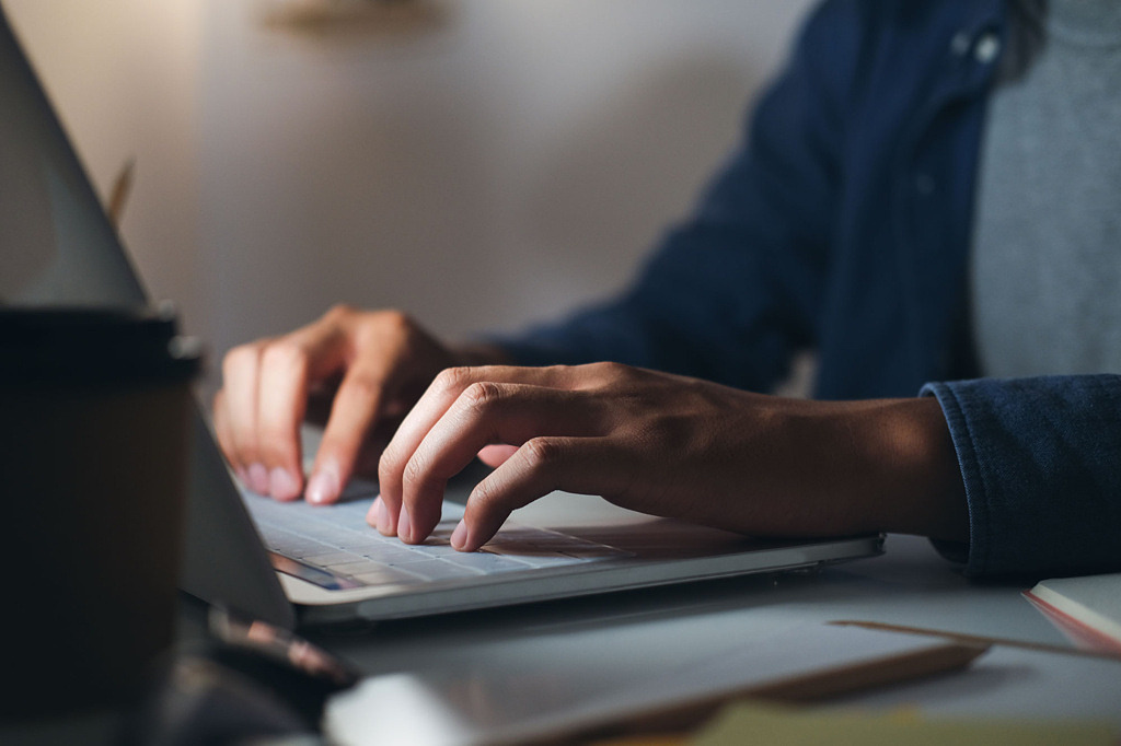Händer som skriver på tangentbordet på en laptop.