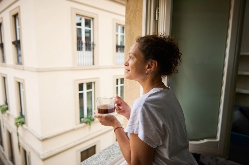 Lärare som dricker kaffe och blickar ut genom fönstret, symboliserar avkoppling och ekonomisk trygghet från Lärarnas a-kassa och Sveriges Lärare.
