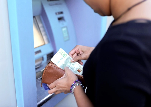 Person tar ut pengar från en bankomat, vilket kan vara ersättning från Lärarnas a-kassa.