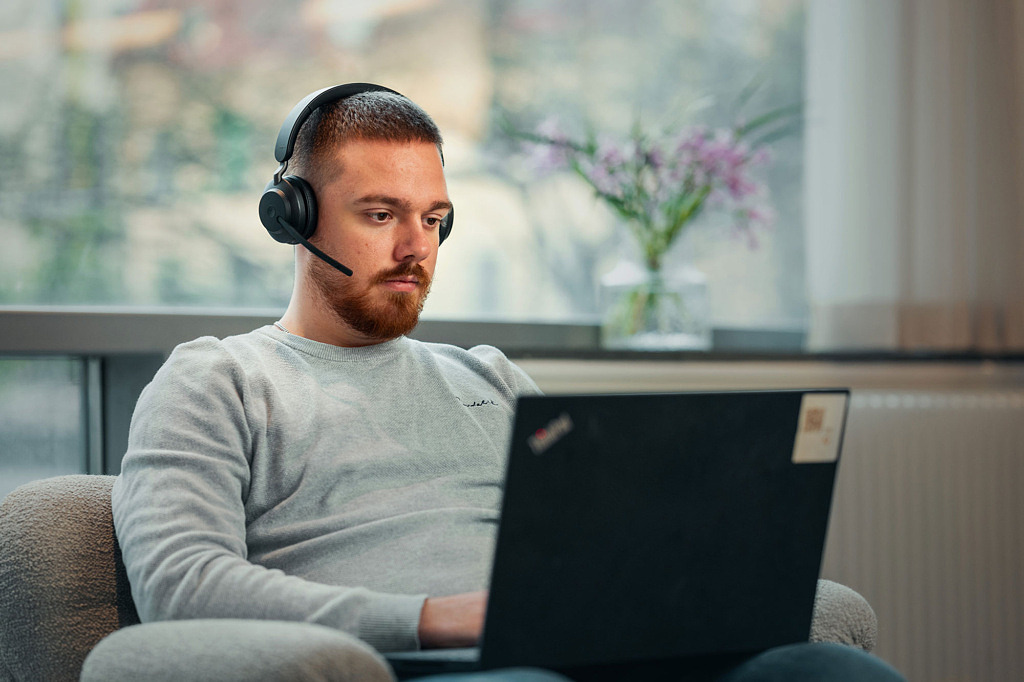 Medarbetare på Lärarnas a-kassa arbetar vid sin laptop med headset på sig.