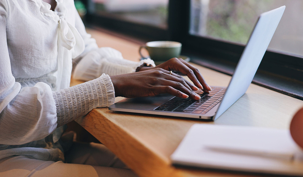 En kvinnas händer använder tangentbordet på en laptop.