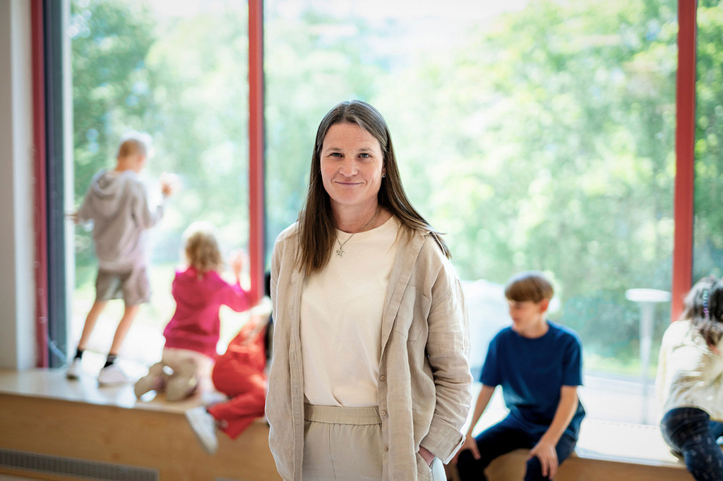 Lärare står framför elever som sitter på en bänk.